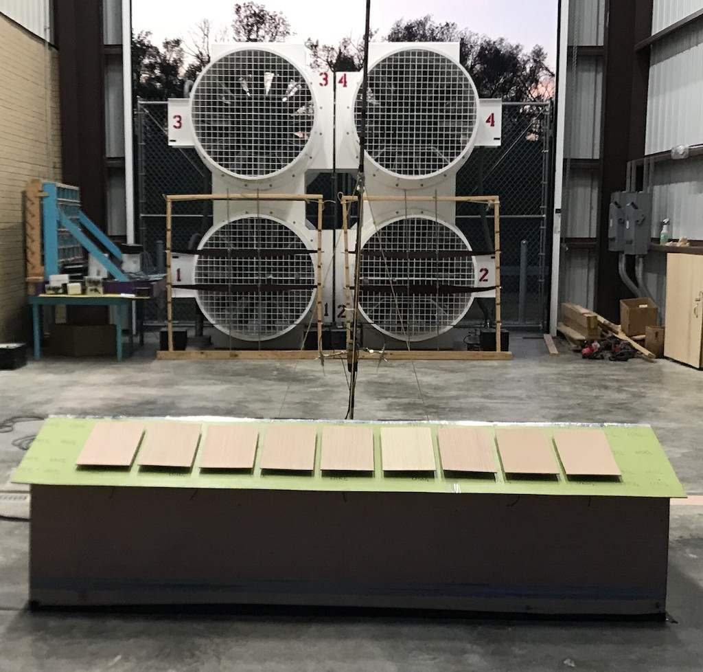 A low-rise building model with rooftop solar panels in front of the fan array
